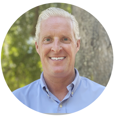 Smiling man in a blue shirt outdoors.