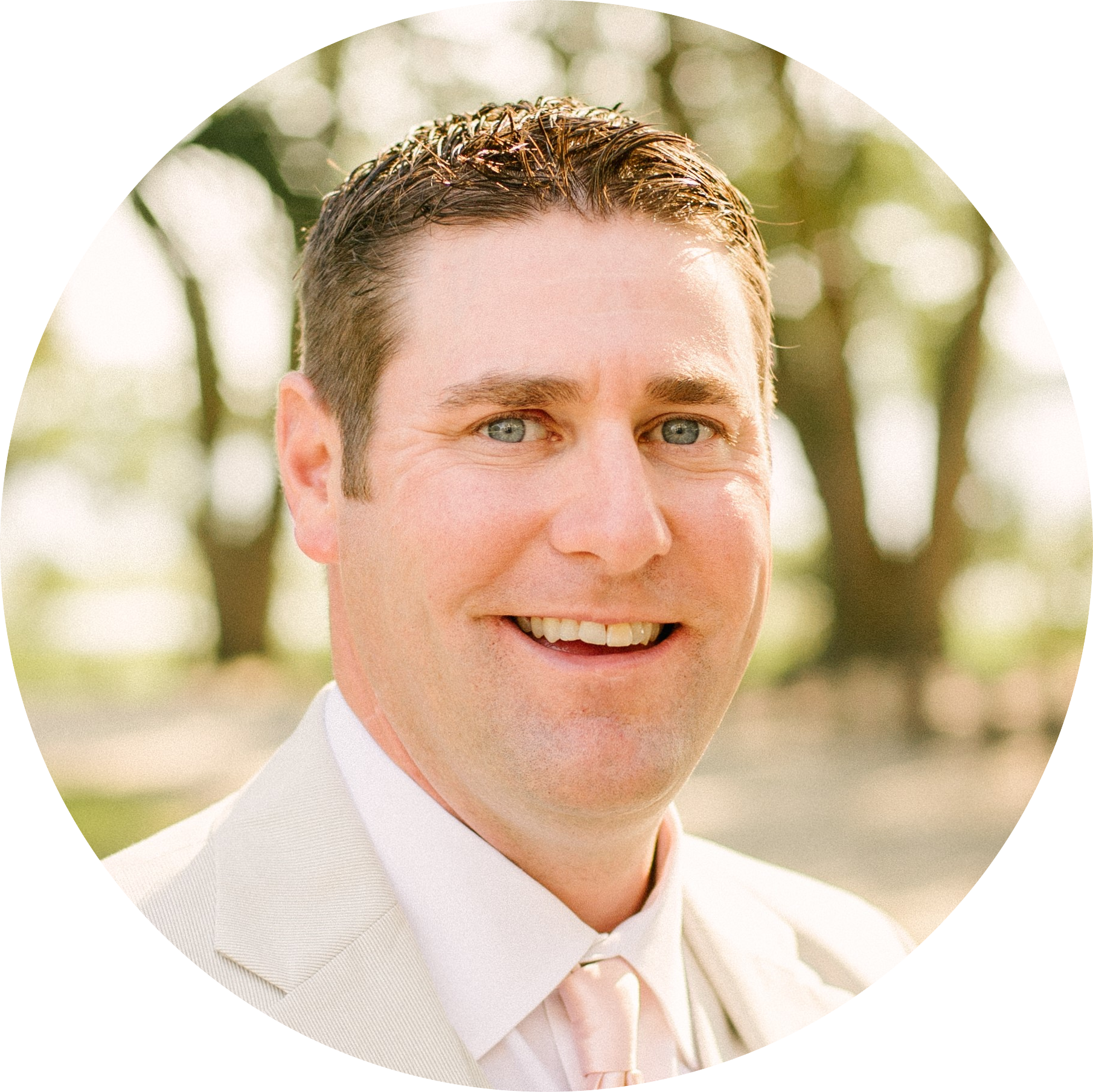 Smiling man in a light suit outdoors.